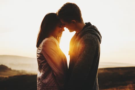 jeune couple s'embrassant au coucher du soleil